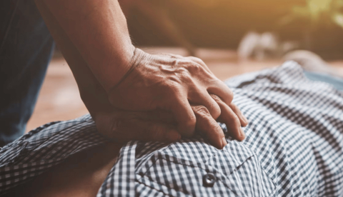  Un hombre posa las manos sobre el pecho de otro hombre tumbado. Maniobras de reanimación cardiopulmonar. PanuShot/Shutterstock