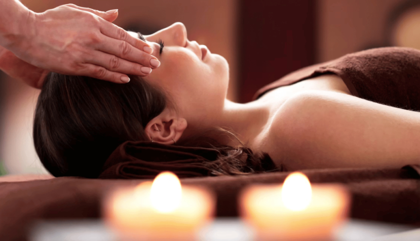  Alguien coloca las manos en las dos sienes de una mujer. El reiki se basa en canalizar algo que llaman qi (una supuesta “energía vital”, carente de respaldo científico) mediante la imposición de manos a escasos centímetros de la persona. Andrey_Popov/Shutterstock