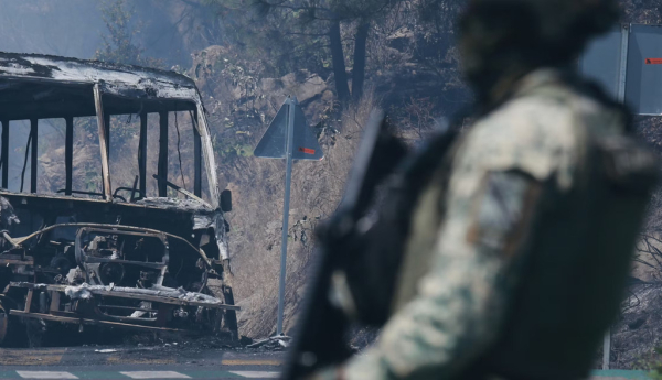 A soldier stands guard by a charred vehicle in Michoacán state, Mexico, on Feb. 22, 2026. AP Photo/Armando Solis