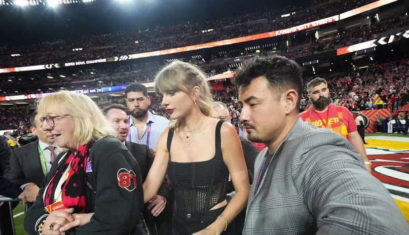 Taylor Swift, flanked by security guards and Donna Kelce, mother of her boyfriend, Travis Kelce, appears at the Super Bowl in February 2024. Julio Cortez/AP