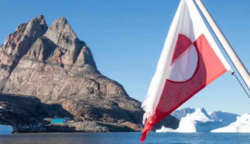 Bandera de Groenlandia con montañas y glaciares al fondo. Michal Balada/Shutterstock