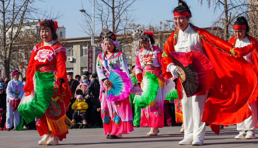  Personas con trajes coloridos bailan en la calle. Algunas personas bailan yangko en Luannan, para celebrar el tradicional festival de Primavera chino, en febrero de 2025. chinahbzyg/Shutterstock