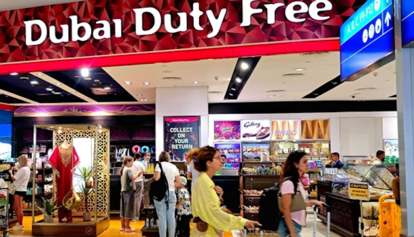  Gente con maletas junto a un establecimiento con el rótulo "Dubai duty free" Aeropuerto de Dubái. shanid chirammal house/Shutterstock