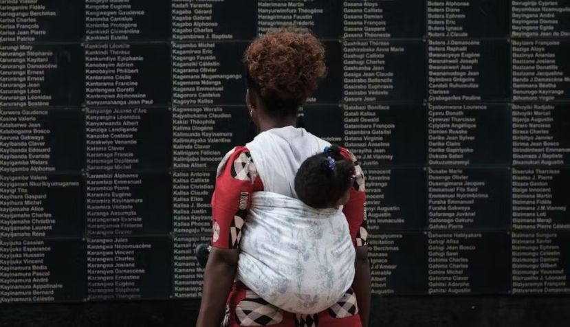 Una mujer con un niño en brazos observa un muro en Kigali con los nombres de las víctimas del genocidio de Ruanda de 1994. Yasuyoshi Chiba/AFP via Getty Images
