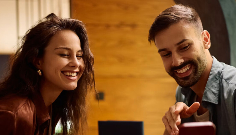  Un chico y una chica miran sonrientes un móvil Drazen Zigic/Shutterstock
