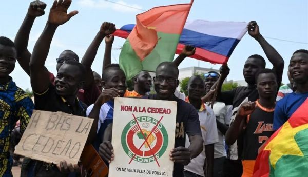 A small group of protesters holds Russia and Burkina flags as they protest against the Economic Community of West African States (ECOWAS). Issouf Sanogo/AFP via Getty Images