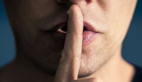  Un hombre se pone el dedo en los labios en ademán de mandar que se guarde silencio. Tero Vesalainen/Shutterstock
