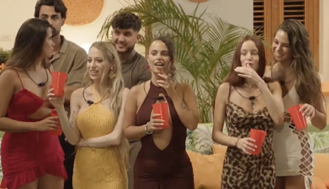  Un grupo de mujeres con vestidos ajustados se mira y habla entre ellas. Momento del programa televisivo La isla de las tentaciones. Mediaset.