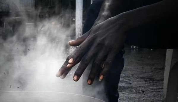 Un jeune soudanais se réchauffe les mains dans un camp de migrants à Ouistreham, dans le nord de la France. Photo prise pour un reportage de Mathieu Clavel. Lou Benoist/AFP