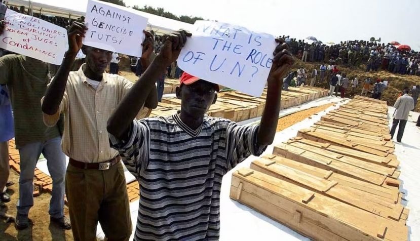 Men hold up protest signs in front of the coffins of DRC refugees killed in August 2004 in Gatumba, Burundi. Simon Maina/AFP via Getty Images