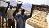 Men hold up protest signs in front of the coffins of DRC refugees killed in August 2004 in Gatumba, Burundi. Simon Maina/AFP via Getty Images